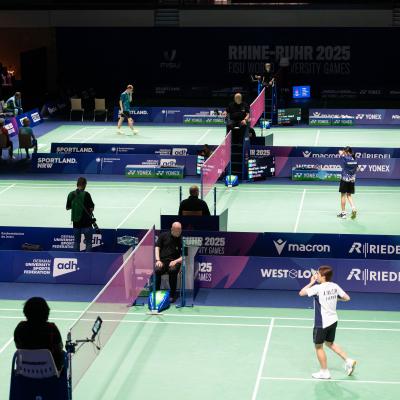 Badminton-Spieler bei der FISU auf einem grünen Spielfeld in der Mülheimer Westenergie Sporthalle