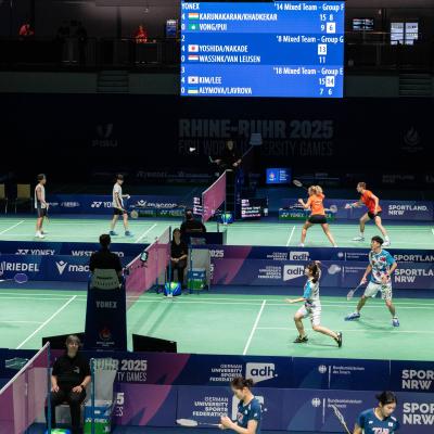 Badminton-Spieler bei der FISU auf einem grünen Spielfeld in der Mülheimer Westenergie Sporthalle