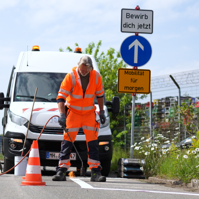 Ein Mitarbeiter des Bauhofs bringt eine Markierung auf die Straße auf.