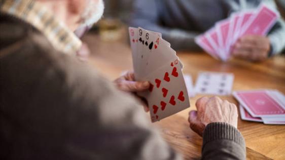 Kommentar Nahaufnahme eines nicht erkennbaren älteren Menschen, der Karten spielt.