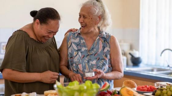 Betreuerin und ältere Dame kochen und lachen zusammen. Informationen zu Entlastung im Alltag bei der Haushaltsführung, Entlastung im Alltag durch individuelle Hilfen. Senioren, Seniorinnen