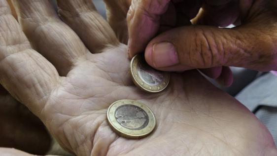 Hände eines alten Menschen, eine Hand dreht zwei 1-Euro-Geldstücke in der anderen Hand um. Senioren, Seniorinnen, Altersarmut, Rente