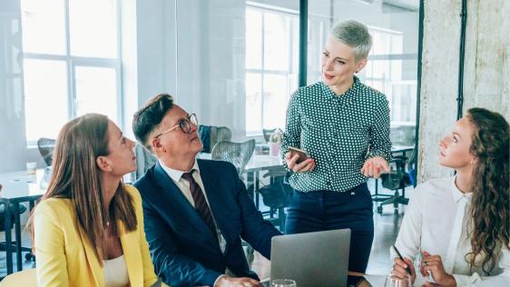 Drei Frauen und ein Mann besprechen sich während eines Meetings in einem Büro.