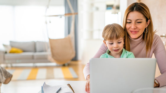 Mutter mit Sohn schaut auf den Laptop und lachen freundlich.