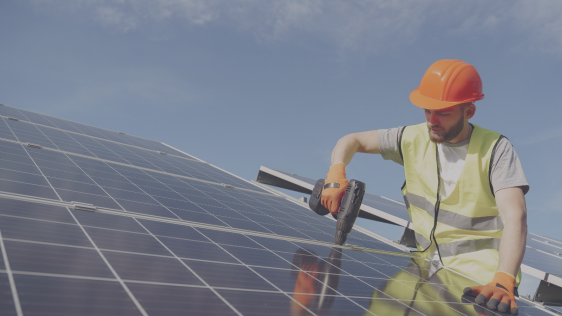 Ein Handwerker montiert ein PV-Modul auf einem Dach.