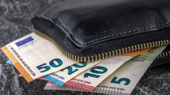 Brieftasche mit geöffnetem Reißverschluss, aus der Geldstücke und Scheine herausgucken. Stichwörter: Portmonee, Gehalt, Lohn, Ausbildungsvergütung, Geldbörse, Euros, Kleingeld, bezahlen, Finanzen, Bußgeld, Steuern