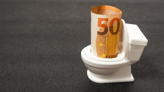Ein gerollter 50 Euro-Schein in einer Modelltoilette.