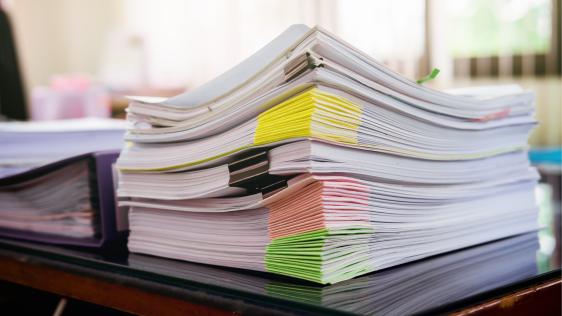 Mehrere aufgehäufte Papierstapel mit verschiedenfarbigen Markierungen.