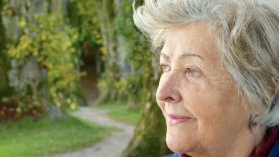 älter Dame, die in einem Park steht