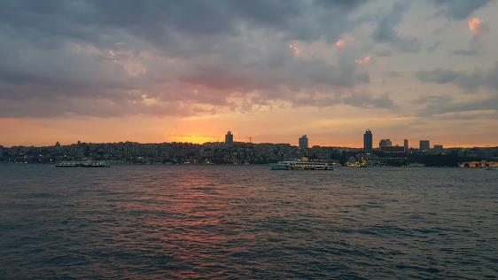 Blick auf den Bosporus, an dessen nördlichen Ende die türkische Partnerstadt Beykoz liegt, mit vorbeifahrenden Fähren bei Abendlicht.