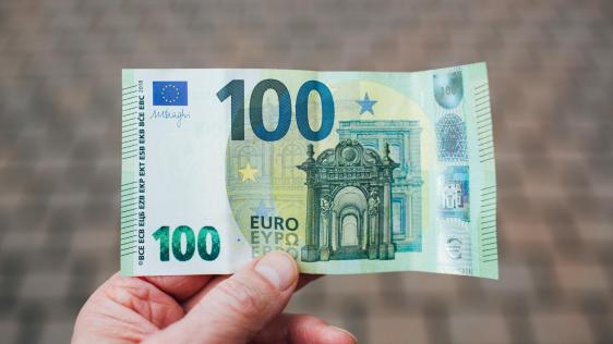 Eine Hand hält einen 100 Euro-Schein.