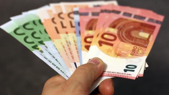 Eine abgebildete Hand die Geldscheine festhält.