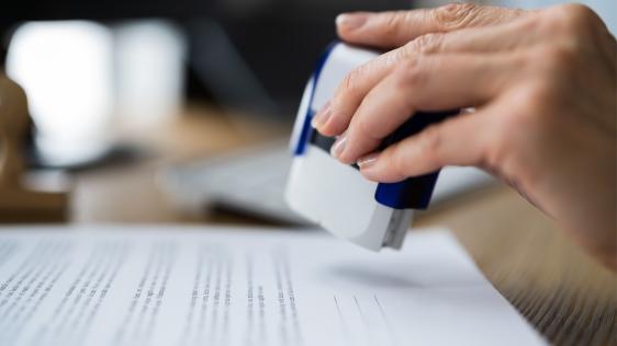 Eine Hand hält einen Stempel über ein Formular.