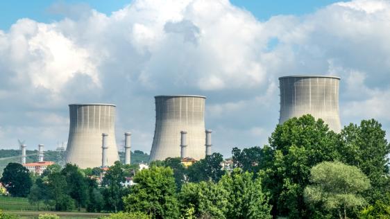Das Bild zeigt drei große Kühltürme die Rauch ausstoßen