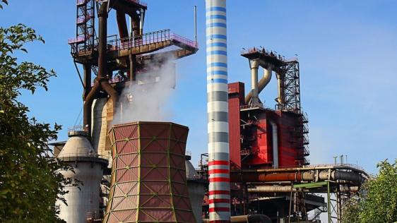 Industrieanlage mit rauchenden Schornsteinen.