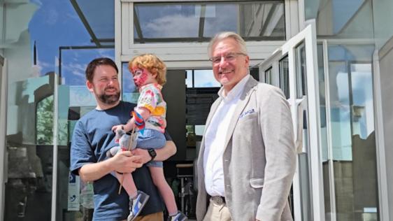 Oberbürgermeister Marc Buchholz (rechts) und Dr. Frank Pisani mit dem kleinen Besucher, Niclas, vor dem Gesundheitsamt