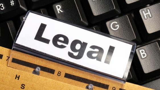 Ein Aktenordner mit der Aufschrift "Legal" liegt auf einer Tastatur.