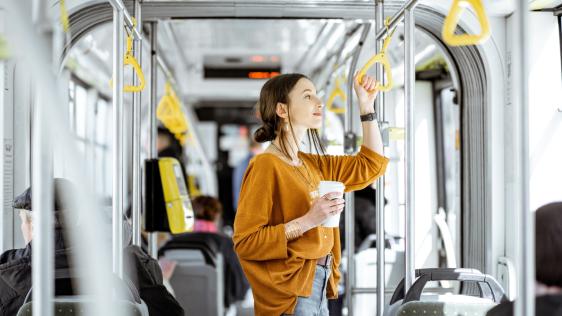 eine Frau steht mit einem Kaffe in der Hand in einem Bus 