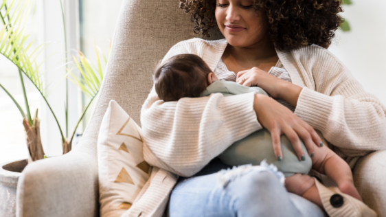 Frau sitzt im Sessel und stillt ihr Baby