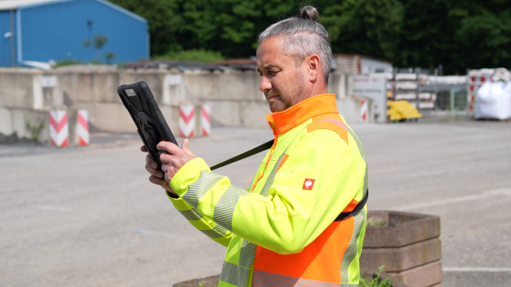 Ein Mitarbeiter des Bauhofs prüft sein Tablet für eine anstehende Straßeninspektion.