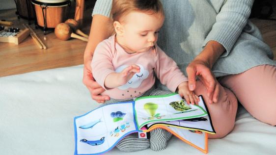 Tagesmutter schaut mit einem Kleinkind in ein Bilderbuch. Kinderbetreuung, Tagesmutter / Tagesvater gesucht!