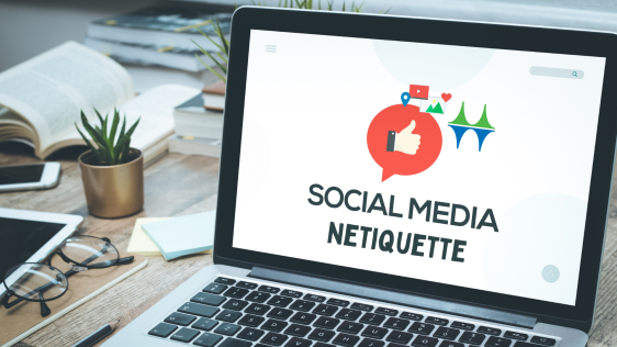  Auf einem Schreibtisch steht ein aufgeklappter Laptop. Der Bildschirm zeigt eine Grafik mit der Aufschrift "Social Media Netiquette".