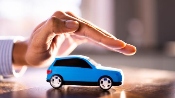 eine Hand schwebt schützend über einem Spielauto