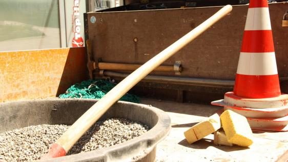 Ausschnitt einer Baustelle mit Pylonen, Kies, Baumaterial.