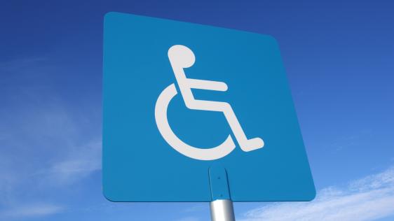 Das blaue Schild eines Behindertenparkplatzes.