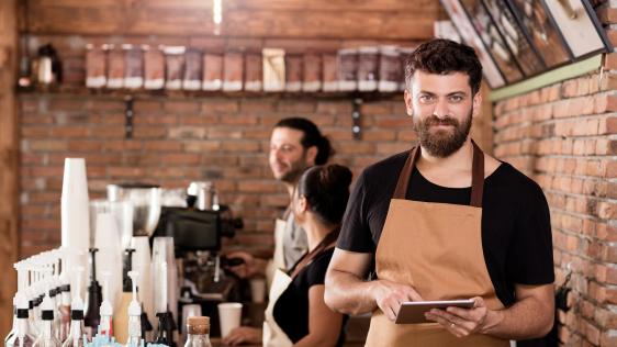 Drei Mitarbeiter*innen stehen in einem Cafe