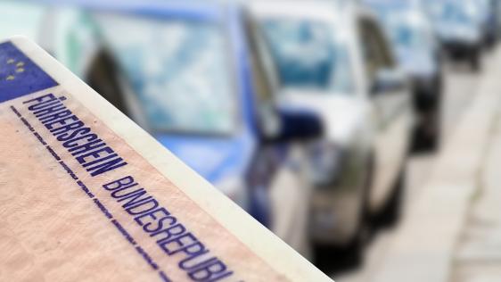Im Hintergrund ist eine Reihe von Autos zu sehen, in der vorderen linken Ecke ist ein Führerschein zu sehen.