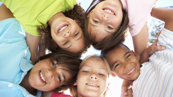 Fünf Kinder schauen, im Kreis aufgestellt, von oben in die Kamera.