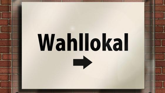 ein Schild auf dem "Wahllokal" steht und Pfeil nach rechts zeigt