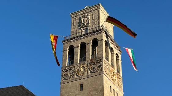 Der Mülheimer Rathausturm ist beflaggt. Die Beflaggung umfasst die Flaggen Europa, Deutschland, Land Nordrhein-Westfalen und Stadt Mülheim an der Ruhr.