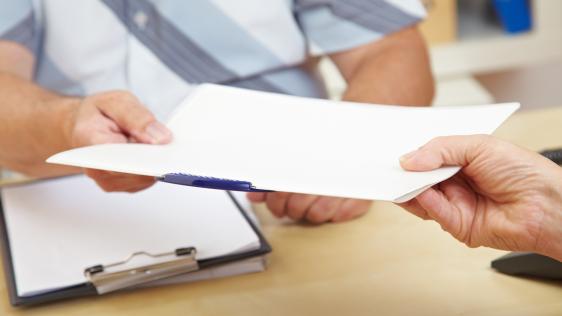eine Person reicht einer anderen Person Papier