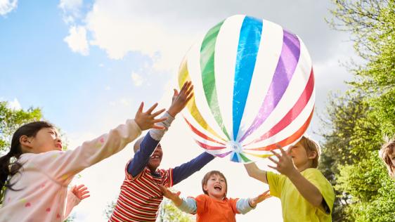 vier Kinder, die einen Ball hochhalten