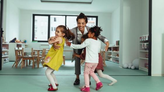 Tagesmutter spielt und tobt mit Kindern in den Räumen des Tagespflegenestes. Kindertagespflegepersonen, Kita, Kindergarten, Kinderbetreuung, Pflegevater, Pflegemutter