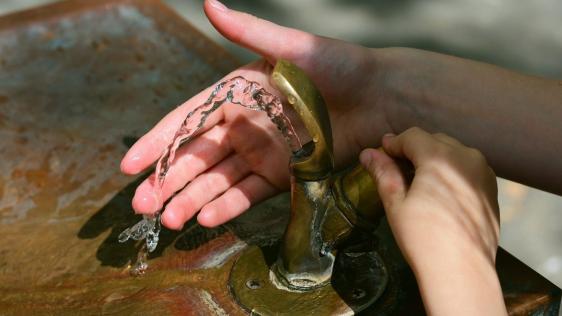 Hände am einem Brunnen mit Trinkwasser.