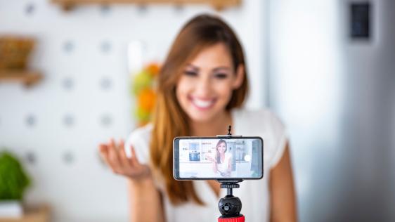 eine Dame die ein Handy mit einem Stativ aufgestellt hat und sich selbst filmt
