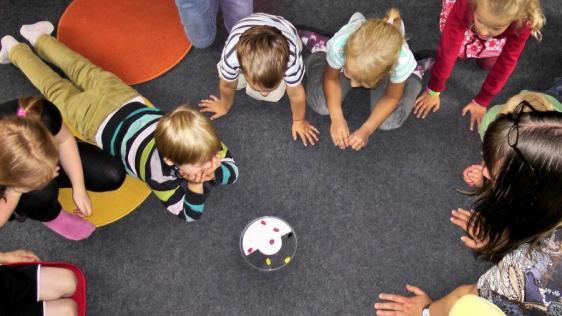 Betreuerin spielt mit Kindern. Infos für Kindertagespflegepersonen.