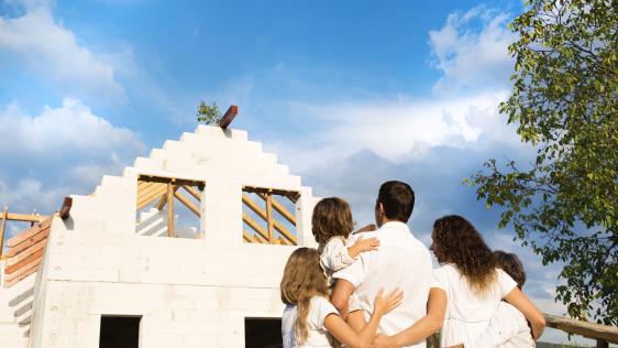 Eine Familie schaut sich ihr halbfertiges Haus an.