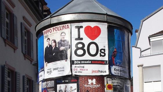 Bildausschnitt einer Litfasssäule mit verschiedenen Werbeplakaten für Konzerte und andere Veranstaltungen.