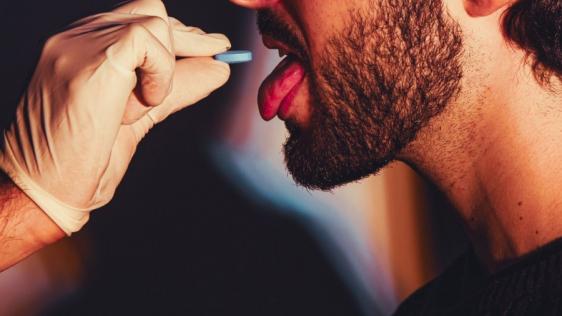 Ein Mann nimmt eine blaue Tablette ein, die ihm von einem Arzt verabreicht wird.