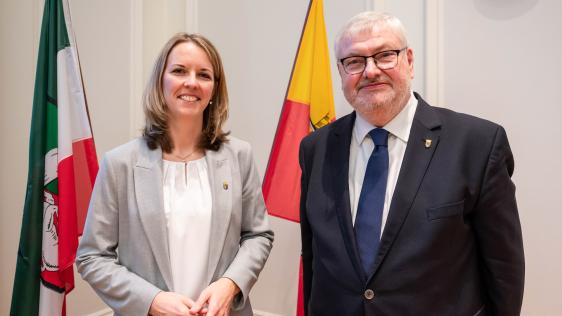Ehrenamtliche Stellvertreterin Alexandra Hanf und Stellvertreter Markus Püll stehen vor der Mülheim Flagge im Ratssaal. 