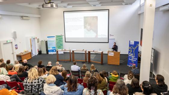 Die Abbildung zeigt den Referenten Hakan Caliskan und das Publikum