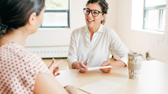 2 Frauen führen an einem Tisch ein Beratungsgespräch