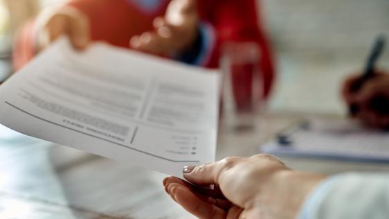 Nahaufnahme einer Bewerbung, die von einer Hand zur anderen gereicht wird