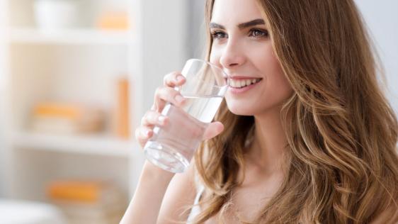 Eine junge Frau mit einem Wasserglas in der Hand.