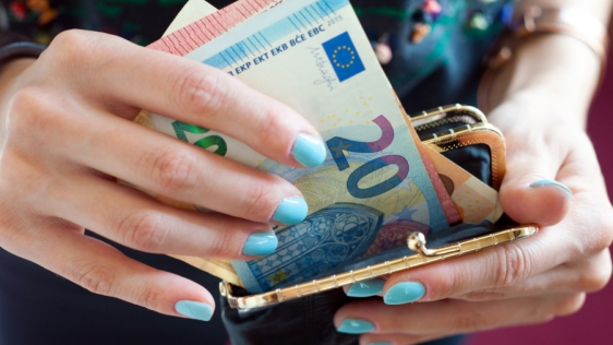 Hände einer Frau, die Geldscheine aus einer Geldbörse nehmen