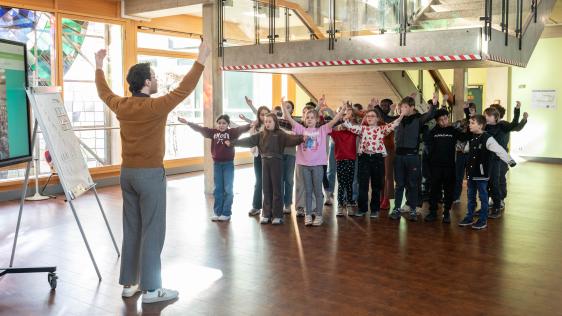 Singleiter leitet eine Grundschulklasse bei der Vorführung des Projektes SingPause an.